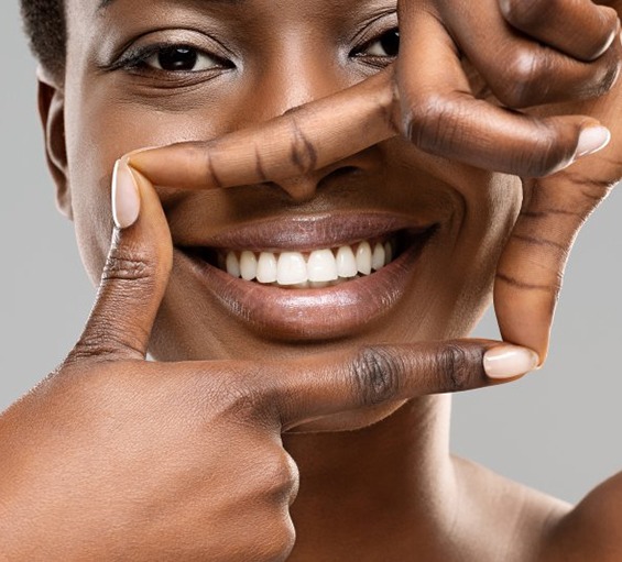 Young woman framing a box around her smile with her fingers