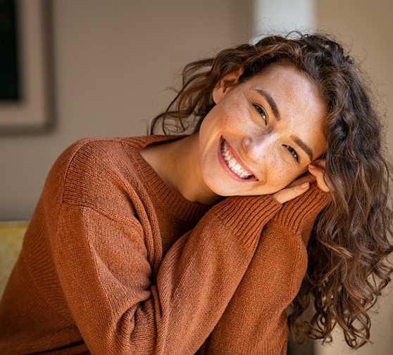 Young woman leaning forward on hands and smiling brightly