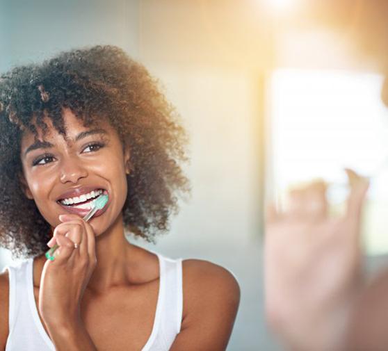 Young woman brushing her teeth to maintain her pearly whites