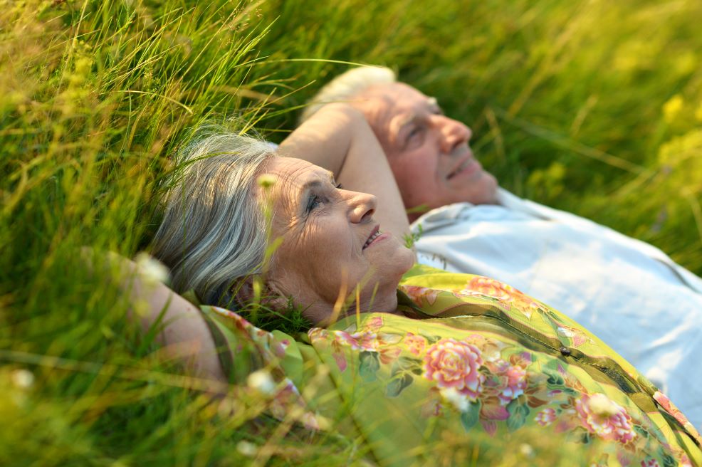 An older man and woman resting in a field.